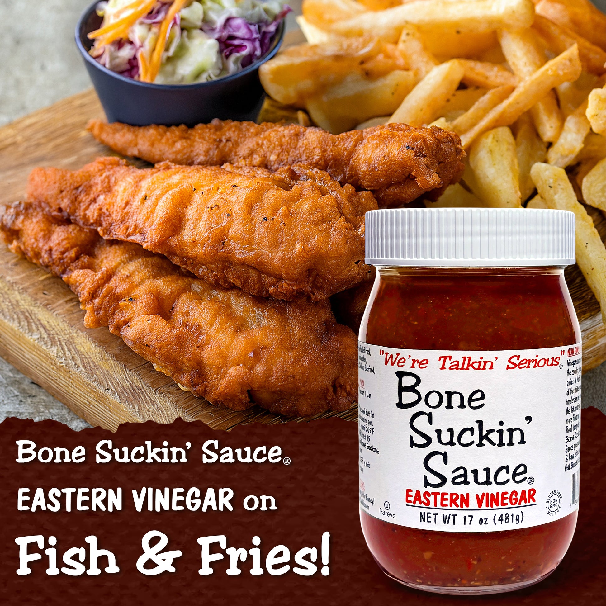 Bottle of Bone Suckin' Sauce with fried fish and fries on a wooden board