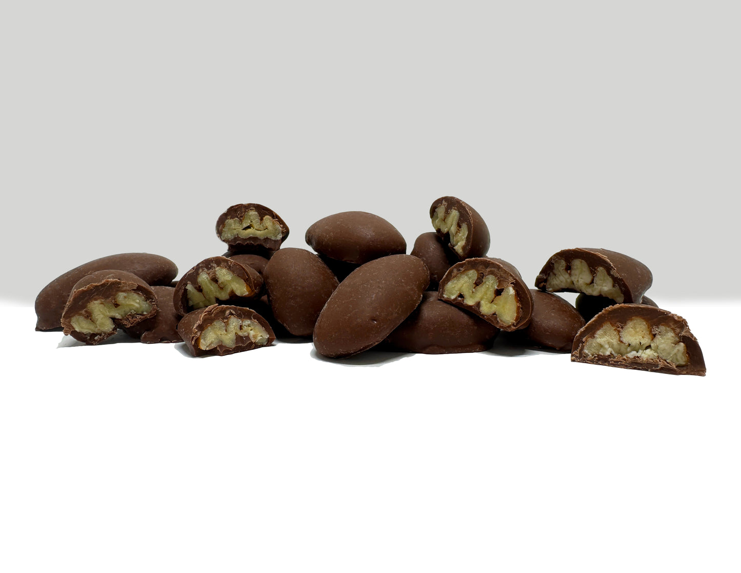 Chocolate Covered Pecans stacked on each other with inside of pecans showing